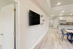 A modern kitchen with white cabinets, a built-in oven, and a dining area with a table and chairs. - Old Bryan Salento - B (Myrtle Beach)