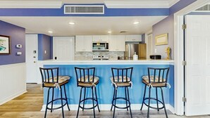 A kitchen with a central island, bar stools, and a white door. - Myrtle Shores Retreat (Myrtle Beach)