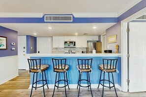 A kitchen with a central island, bar stools, and a white door. - Myrtle Shores Retreat (Myrtle Beach)