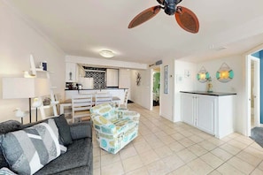 A spacious living area with a sofa, a patterned ottoman, a ceiling fan, and a kitchen in the background. - Sands Beach Club 524 The Chill Pill (Myrtle Beach)