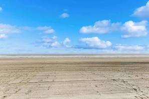 A wide sandy beach with footprints leading towards the ocean under a clear sky. - Sands Beach Club 524 The Chill Pill (Myrtle Beach)