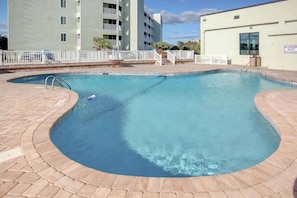 A swimming pool with a curved edge, surrounded by a brick deck. - Sands Beach Club 524 The Chill Pill (Myrtle Beach)