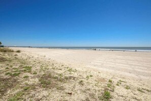 A beach with a clear sky, a sandy shore, and a few people in the distance. - Sands Beach Club 524 The Chill Pill (Myrtle Beach)