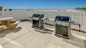 Een terras buiten, met twee barbecues en een picknicktafel.