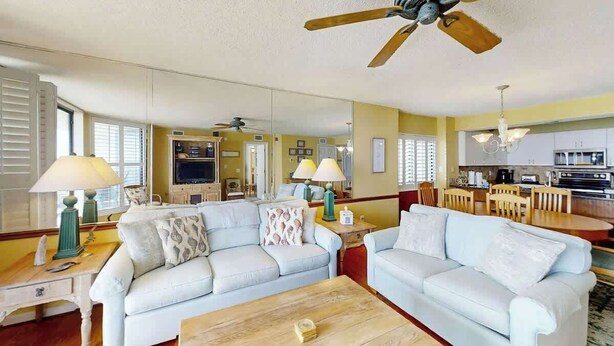A living room with two light-colored sofas, a wooden coffee table, and a ceiling fan. - Little Big House at Windy Hill (North Myrtle Beach)