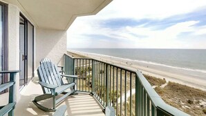 A balcony with a view of the beach, a chair, and a railing. - Little Big House at Windy Hill (North Myrtle Beach)