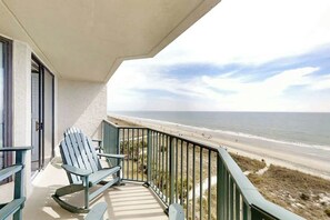 A balcony with a view of the beach, a chair, and a railing. - Little Big House at Windy Hill (North Myrtle Beach)