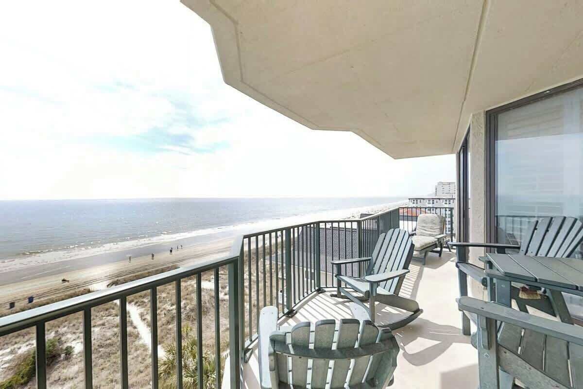 A balcony with a view of the beach and ocean.