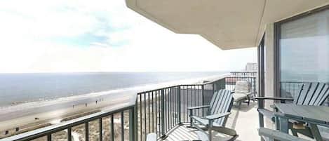 A balcony with a view of the beach and ocean.