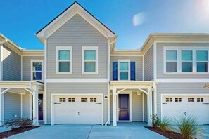 A two-story residential building with a central garage door, a covered entryway, and a small front yard with landscaping. - Double Eagle Unit 5119 (North Myrtle Beach)