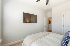 A bedroom with a bed, a wall-mounted TV, and a door leading to another room. - Double Eagle Unit 5119 (North Myrtle Beach)