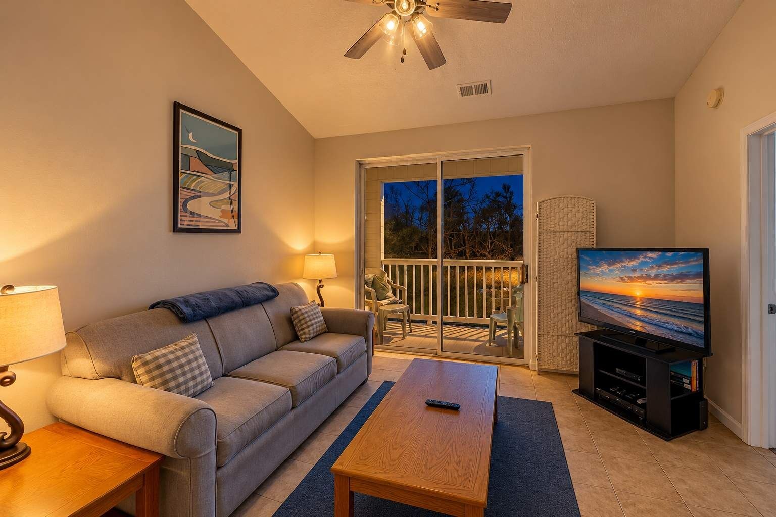 A living room with a sofa, a coffee table, a television, and a ceiling fan.