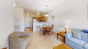 A living room with a sofa, a coffee table, and a dining area with chairs and a table. - River Oaks Unit 61M Condo (Myrtle Beach)