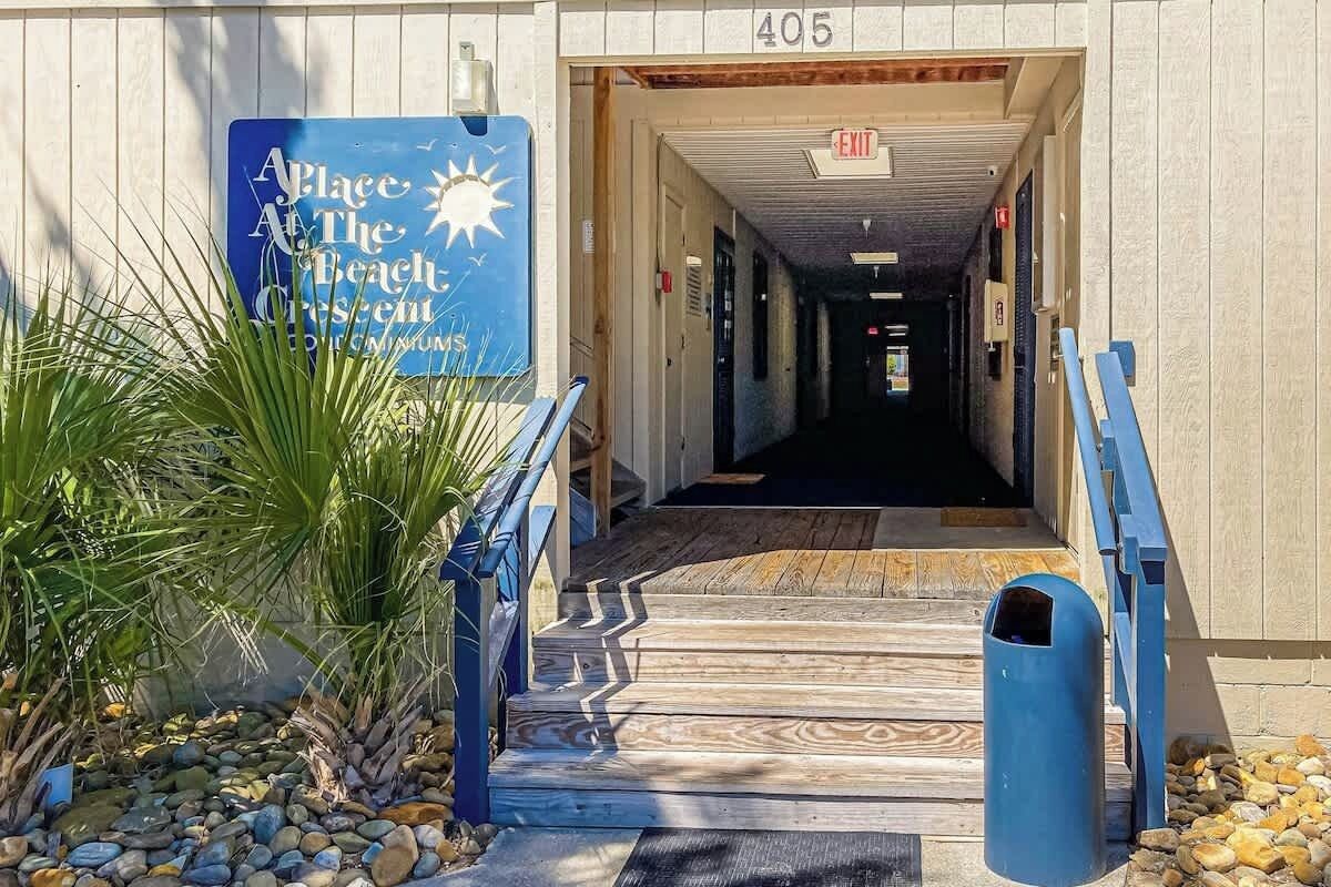 L’entrée d’un immeuble, avec une enseigne indiquant « Place at the Beach » et le numéro « 405 » au-dessus.