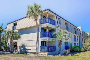 A multi-story residential building with balconies, palm trees, and a clear sky. - Beach Happy Place Retreat (North Myrtle Beach)