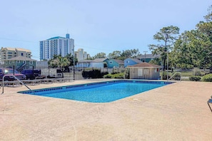 A swimming pool with a fenced area, surrounded by buildings and trees. - Beach Happy Place Retreat (North Myrtle Beach)