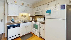 A kitchen with white cabinets, a microwave, a refrigerator, and a dishwasher. - Beach Happy Place Retreat (North Myrtle Beach)