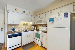 A kitchen with white cabinets, a microwave, a refrigerator, and a dishwasher. - Beach Happy Place Retreat (North Myrtle Beach)