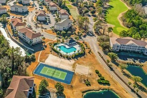 Un barrio residencial con casas, cancha de tenis, piscina y campo de golf.