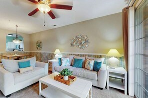 Ein modernes Wohnzimmer mit zwei Sofas, einem Couchtisch und einem Deckenventilator.