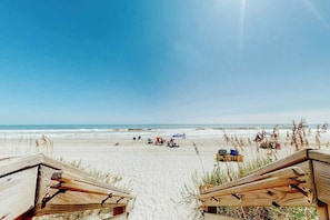 A beach with wooden structures, possibly a beach house or a resort, with a clear sky and ocean in the background. - Ocean Garden Villas G-2 (North Myrtle Beach)
