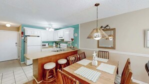 Una cocina con armarios blancos, una mesa de comedor de madera y una lámpara colgante.