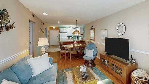 Una sala de estar con sofá, televisor y comedor con mesa y sillas.
