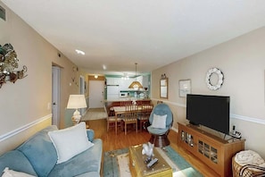 A living room with a sofa, a television, and a dining area with a table and chairs. - Ocean Garden Villas G-2 (North Myrtle Beach)