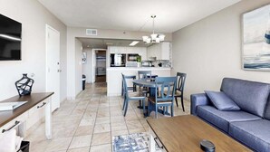 A modern living room with a sofa, a coffee table, and a dining area with chairs and a table. - Sand Dunes Resort 2647 (Myrtle Beach)