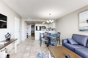 Uma sala de estar moderna com sofá, mesa de centro e área de jantar com cadeiras e uma mesa.