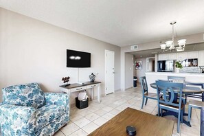 A modern living room with a sofa, a coffee table, a TV, and a dining area with chairs and a table. - Sand Dunes Resort 2647 (Myrtle Beach)