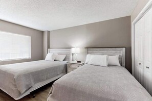 A hotel room with two beds, a nightstand, a lamp, and a wardrobe. - Sand Dunes Resort 2647 (Myrtle Beach)