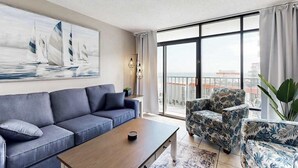 A modern living room with a sofa, a coffee table, and floral-patterned chairs. - Sand Dunes Resort 2647 (Myrtle Beach)