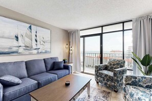 Uma sala de estar moderna com um sofá, uma mesa de centro e poltronas com padrão floral.