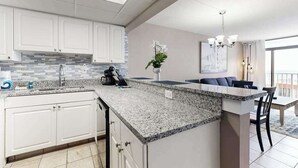 A modern kitchen with white cabinets, a granite countertop, and a built-in island. - Sand Dunes Resort 2647 (Myrtle Beach)