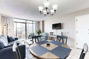 Un salon moderne avec une table à manger ronde, des canapés gris et un lustre.