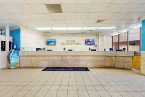 A guest registration desk with a digital screen, a cash register, and a sign for guest registration. - Sand Dunes Resort 2648 (Myrtle Beach)