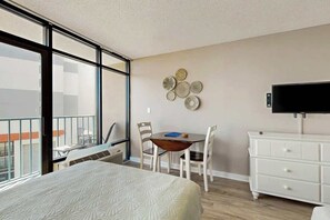A hotel room with a bed, a dining table with chairs, a TV, and a wall-mounted decoration. - Sand Dunes Resort 2648 (Myrtle Beach)