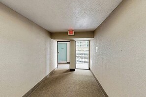 A corridor with a carpeted floor, a light blue door, and an exit sign. - Sand Dunes Resort 2648 (Myrtle Beach)