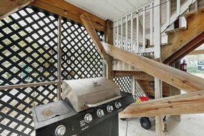 A barbecue grill with a lid and control knobs, positioned under a wooden structure with a lattice design. - Hawleywood Too Retreat (Surfside Beach)