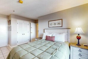 A bedroom with a bed, a nightstand, a lamp, a framed picture, and a wardrobe. - Coffee with a View Retreat (Myrtle Beach)