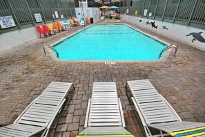 En inomhuspool med ett kaklat golv, en skylt som visar att en badvakt är i tjänst och en väggmålning med ett delfinmotiv.