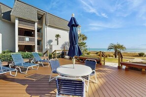 A deck with lounge chairs and a table, overlooking a beach. - Ocean Forest Villas A-216 (Myrtle Beach)
