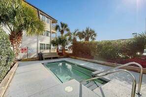 Ein Poolbereich mit einer Bank, Palmen und einem Gebäude mit Balkon.