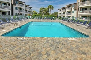 A swimming pool with lounge chairs and a brick deck, surrounded by multi-story buildings with balconies. - Ocean Forest Villas A-216 (Myrtle Beach)