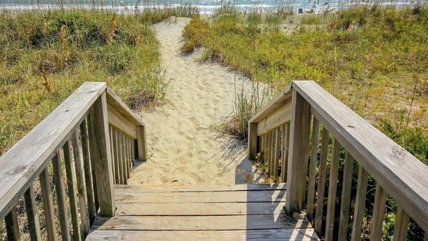 A wooden boardwalk leading to a beach with sand and grass. - Ocean Forest Villas A-216 (Myrtle Beach)