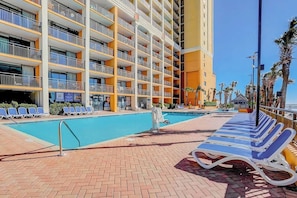 A hotel with a pool area, multiple balconies, and sun loungers. - Here's Your 5 O'Clock Somewhere (Myrtle Beach)