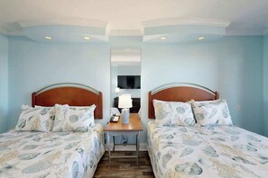 Ein Hotelzimmer mit zwei Betten, einem kleinen Tisch, einer Lampe und einem Spiegel.
