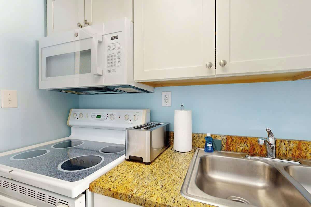 A kitchenette with a microwave, stove, toaster, and sink.