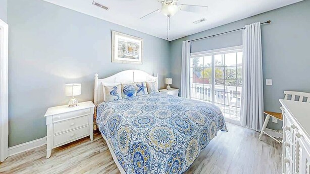 A bedroom with a bed, nightstands, a ceiling fan, and a window with curtains. - Pointe Marsh Unit 2414 (North Myrtle Beach)